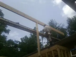 Carpenter setting a ridge beam over a new addition frame — Ice Dam Removal by Roofing Brothers in Goode
