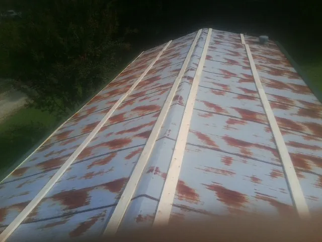 Rusted metal roof panels with new wood purlins before replacement — Storm Damage Roof Repair in Goode by Roofing Brothers