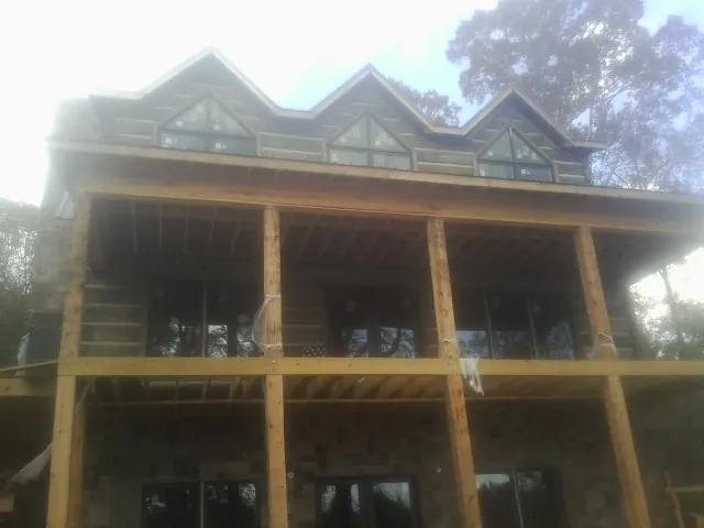 Dormers and porch framing on a large log home under construction — Roof Coating work by our crew in Goode