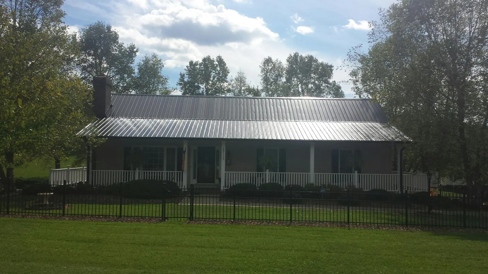 Gray metal roof on a brick ranch with a full width front porch — Gutter Guard Installation work by our crew in Goode