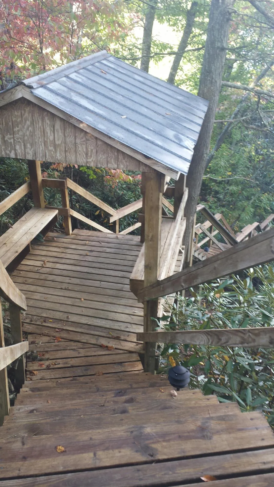 Metal roofed shelter over wooden steps on a wooded walkway — Skylight Repair & Installation work by our crew in Goode