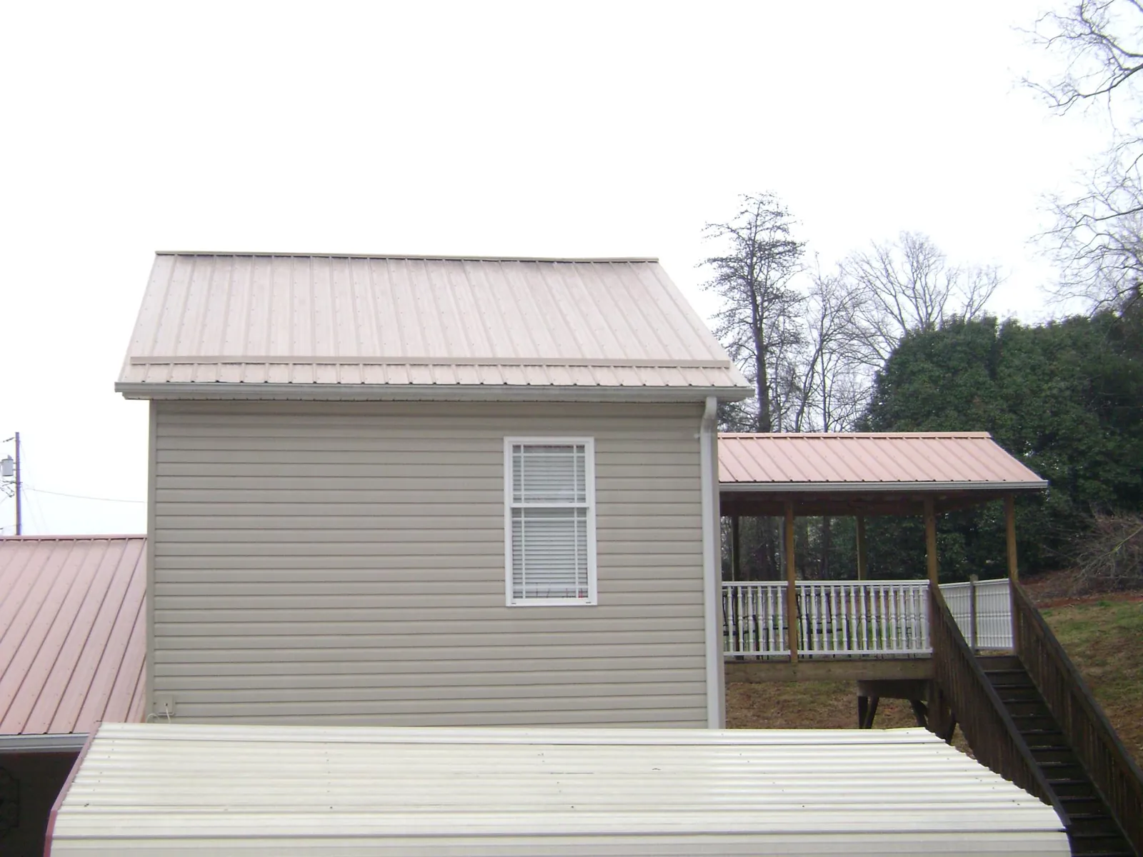Tan metal roofs on a two story addition and attached porch, from a Roof Replacement job in Goode